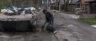 A woman who gave her name only as Nadiya sweeps up around a destroyed Russian armored personnel carrier that has been converted into a dumpster on Thursday, April 21, 2022 in Irpin, Ukraine. Photo Credit:  Brendan Hoffman