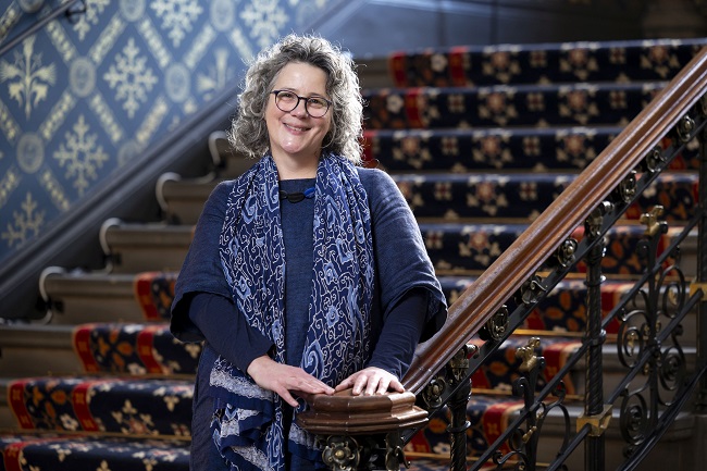 A photograph of Professor Kirsteen McCue standing on a staircase at the University of Glasgow. Credit Martin Shields.