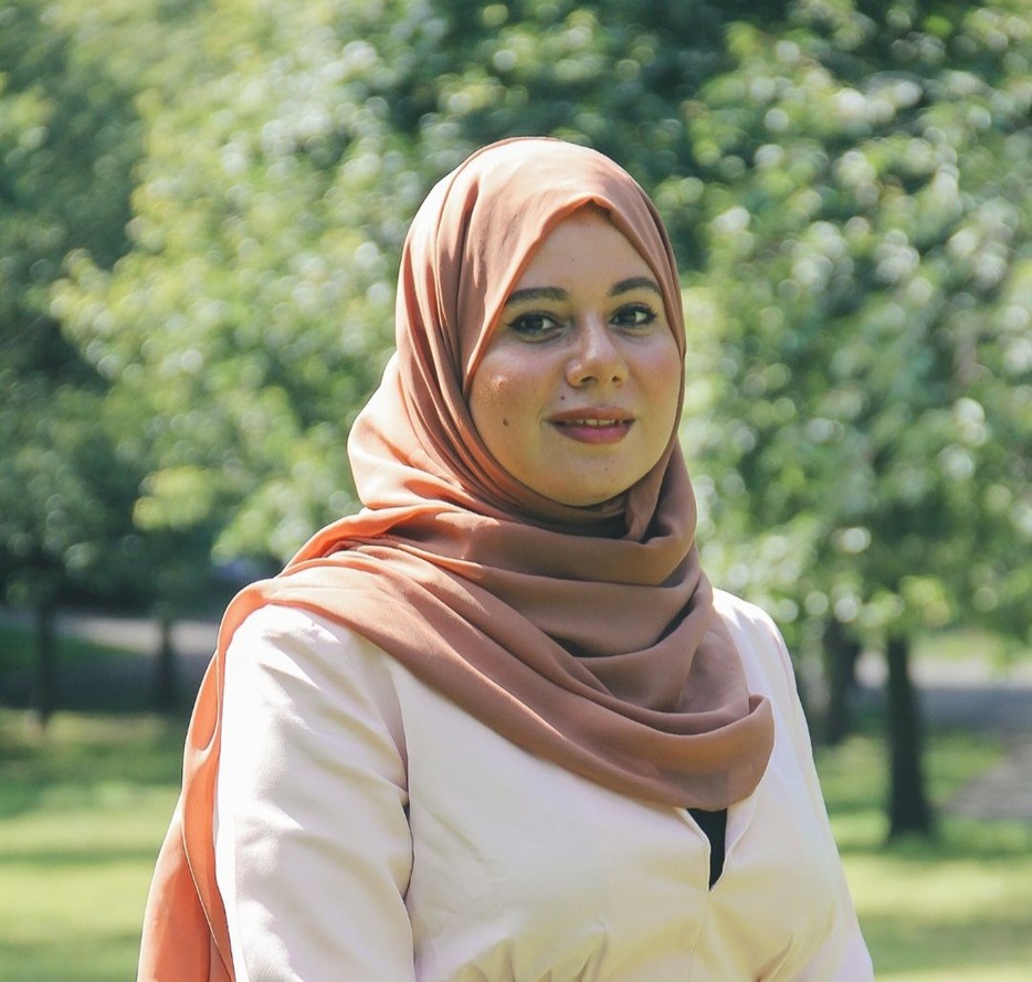 a female student standing in front of green background 