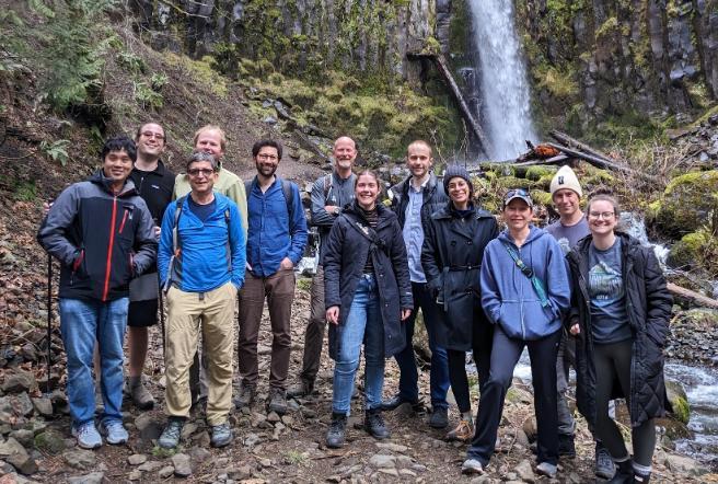 Twelve people stood in front of a waterfall