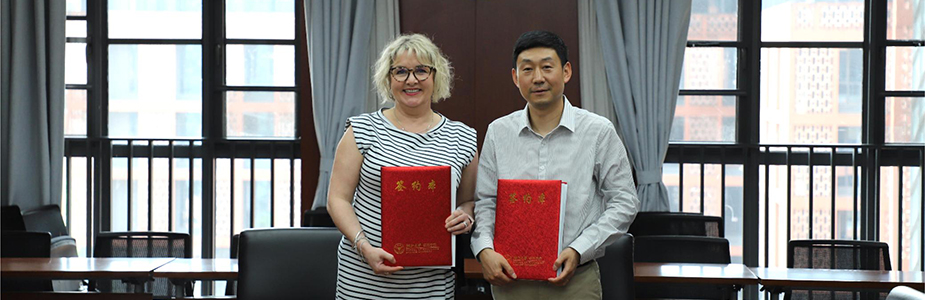 Head of Adam Smith Business School and associate from Zhejiang University standing for a photograph with a signed Memorandum of Agreement