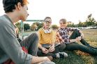 Three adolescents sitting on grass chatting
