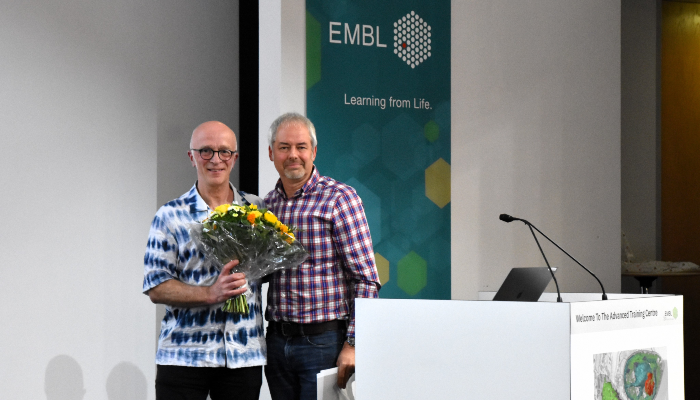 Professor Andrew Waters on stage being presented with a bouquet of flowers