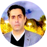 Waqas wears a grey suit and dark jumper. He has short dark hair.