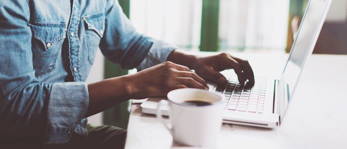 Photo of man using laptop with cup of coffee