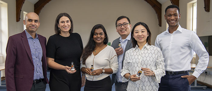 A group photo of business students holding miniature bottles