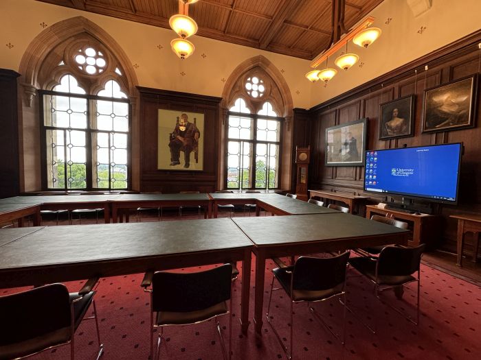 Flat floored meeting room with boardroom table and chairs, and video monitor.