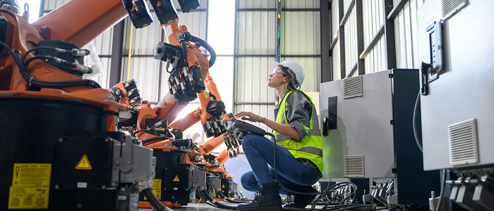 Woman wearing hard hat assessing robotic equipment in warehouse