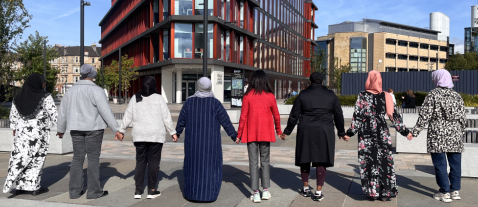  A group of people holding hands outside the Clarice Pears building