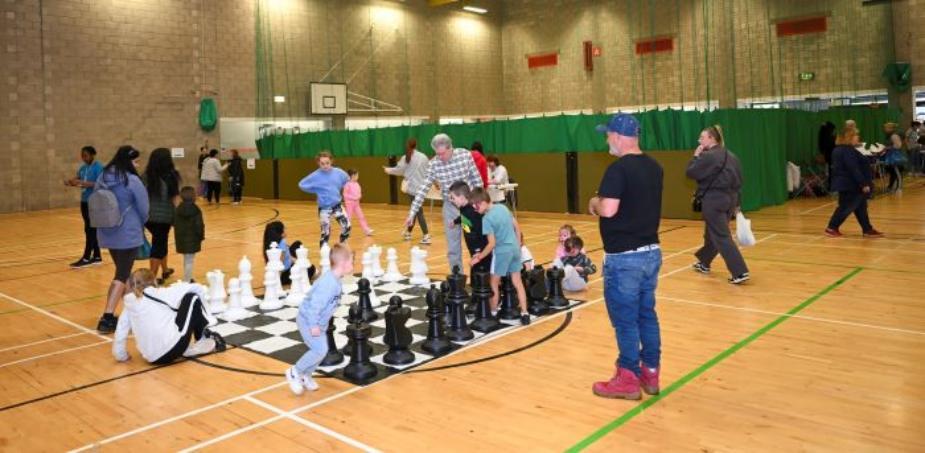 Children and adults playing giant chess in sports hall