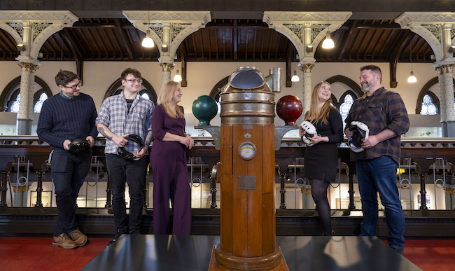 Professor Neil McDonnell, Conor Fraser, Dr Pauline Mackay, Dr Lynn Verschuren and Dr Alan Matthews pose with VR headsets beside a binnacle compass invented by Lord Kelvin on display in The Hunterian