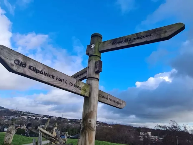 Wooden fingerpost reading, from top to bottom, 'Rome 413 leagues', 'Old Kilpatrick Fort 0.75 leagues', 'Castlehill Fort 0.6 leagues'