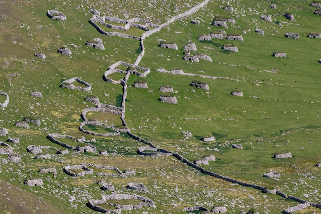 Aerial photo of a grassy slope with many small stone buildings