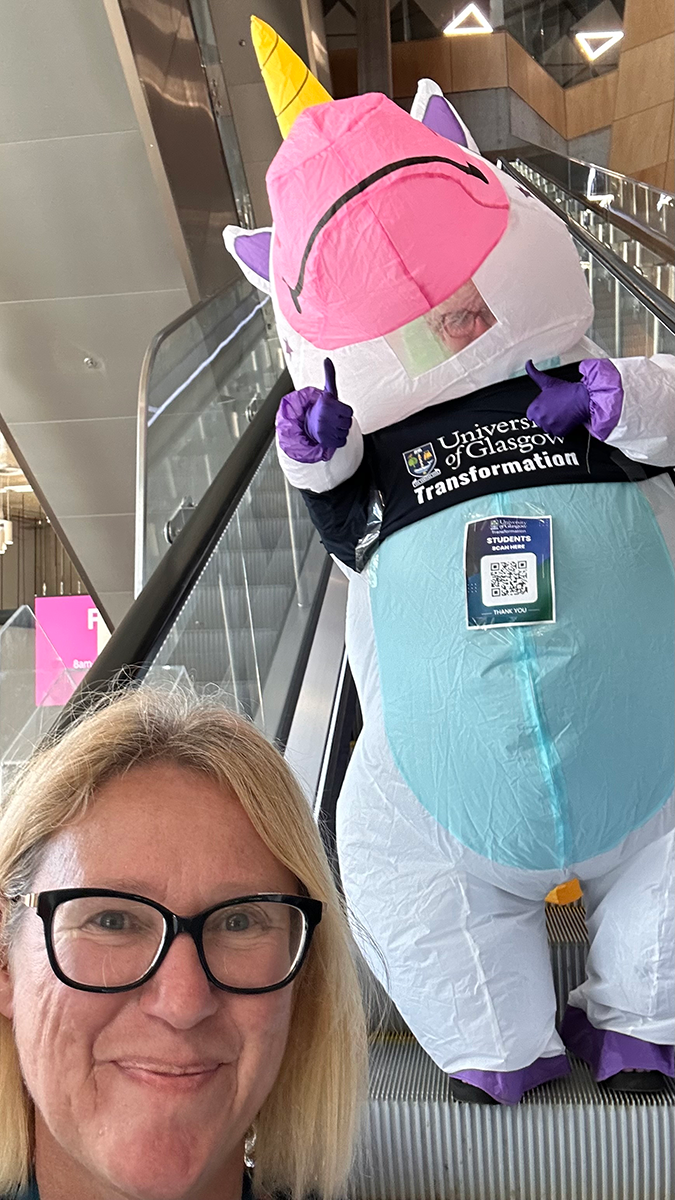 A blonde women taking a selfie with a person in a Unicorn suit