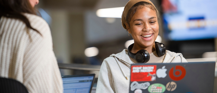 A student smiling while looking at their laptop