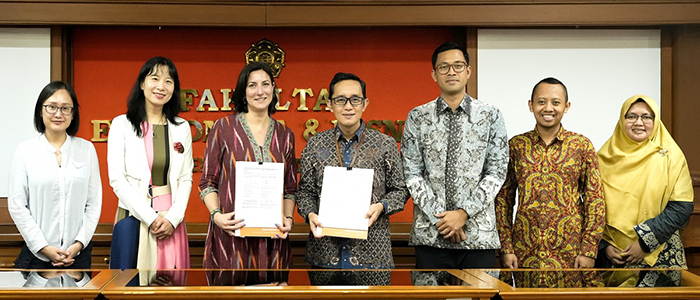 Adam Smith Business School staff and associates at the Faculty of Economics and Business (FEB) at Universitas Gadjah Mada (UGM) standing for a group photo holding signed Memorandum of Agreements