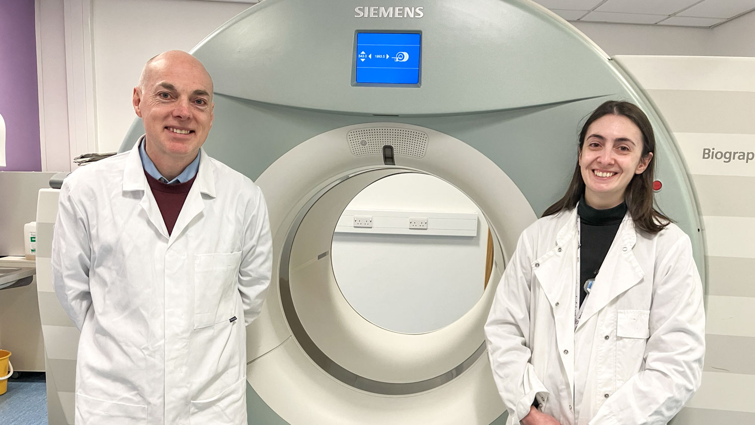 Prof Andy Sutherland and Dr Adriana Tavares in front of a patient scanner at QMRI, Edinburgh