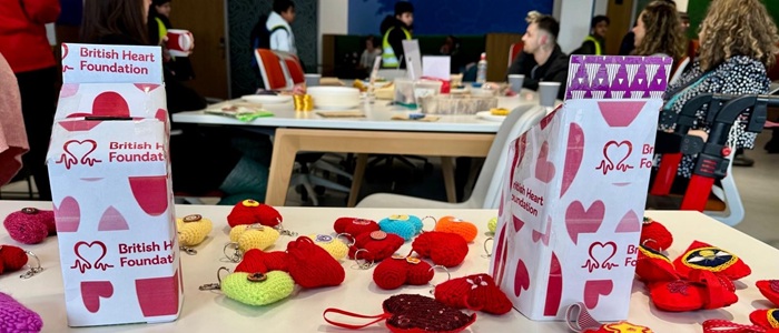 A table with knitted hearts and fundraising boxes for the British Heart Foundation