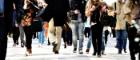 Men and women walking on street. The photo is taken from street level. Two people are checking their mobile phones