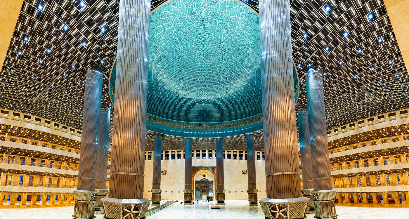 Interior of Istiqlal Mosque showing the huge scale of the building - with a turquoise blue-coloured dome and huge pillars.