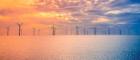 An image of a wind farm off the coast of the UK at sunset
