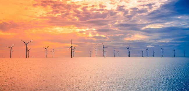An image of a wind farm off the coast of the UK at sunset