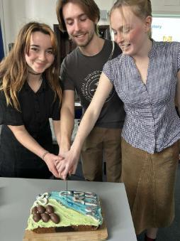 Geography society members cutting cake