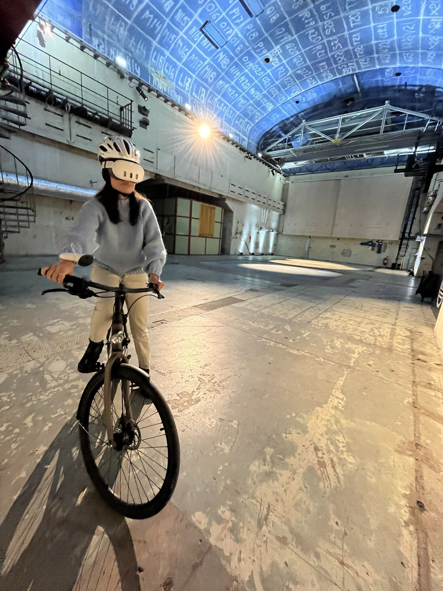 A cyclist rides wearing an AR headset indoors