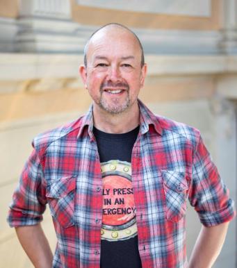 Author Alan Windram standing with his hands on his hips smiling.