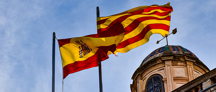 Spanish and Catalan flags flying next to each other in front of a building