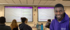 Powerpoint presentations on screen in a classroom with headshot of smiling man