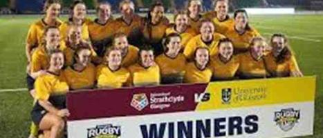 Woman's rugby team celebrating behind winners banner