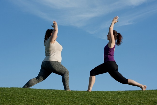 Two women exercising outdoors, doing yoga