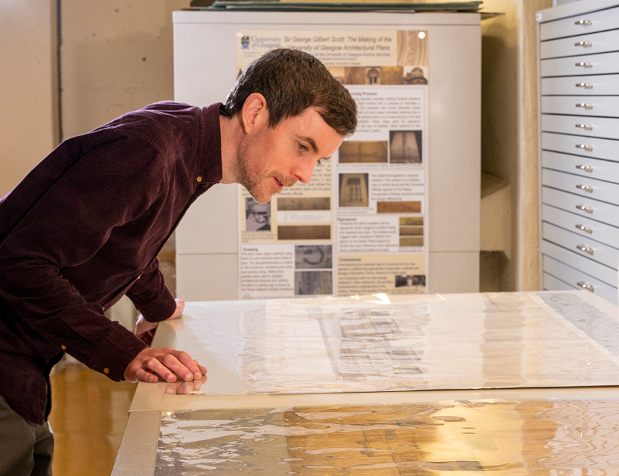 Photo taken from the side of Michael Gallagher surveying the original Gilbert Scott drawings of the Tower in the Archives