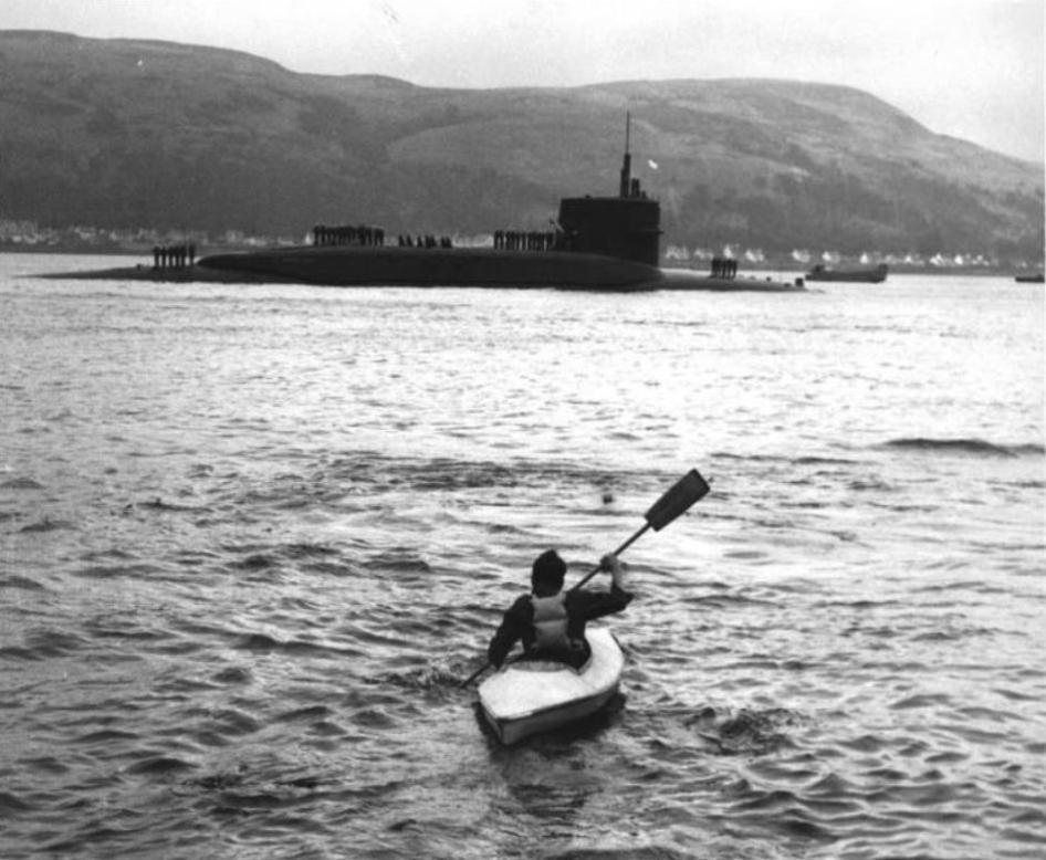 Canoe paddling across the sea towards a submarine