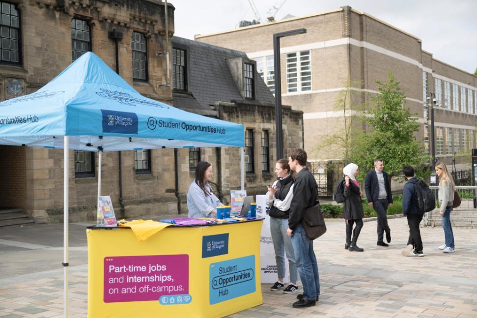 An employer talking to two students at a promotional stand on University Pl