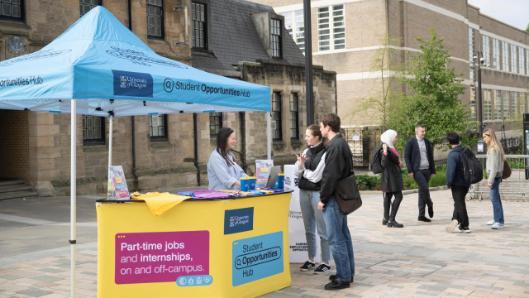 An employer talking to two students at a promotional stand on University Pl