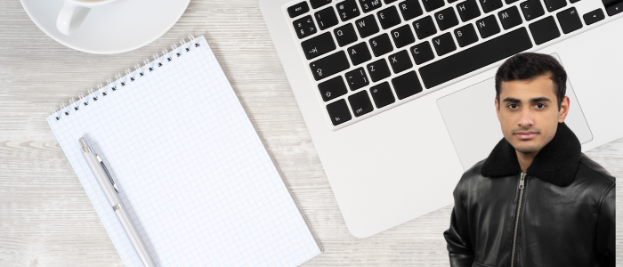 Blank notebook next to a laptop keyboard with headshot of a smiling man