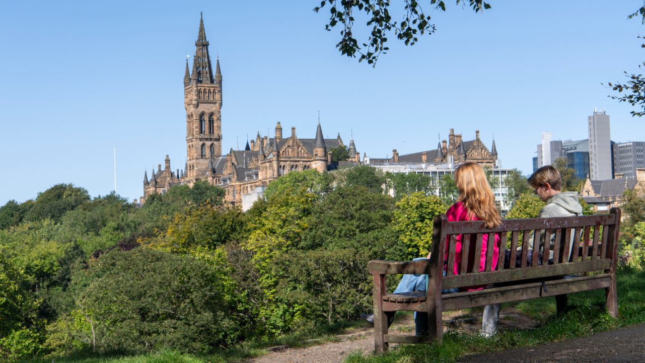 Students in Kelvingrove Park, with University of Glasgow in the distance