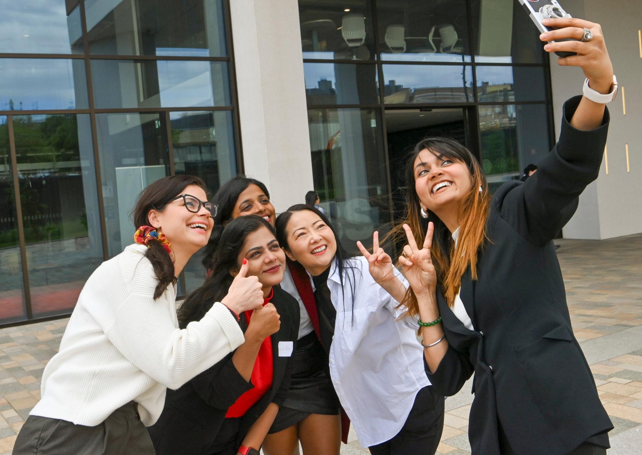 Executive women taking a selfie outside Adam Smith Building