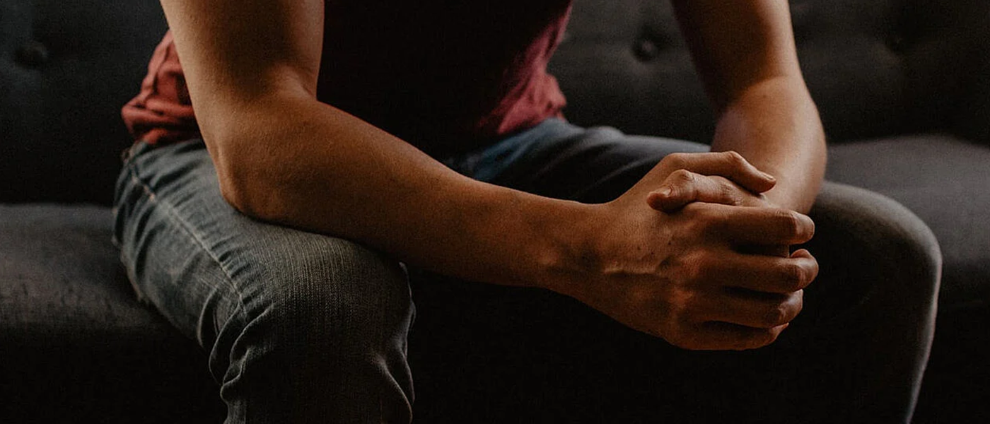 A man sitting forward with his hand together and his elbows leaning on his knees