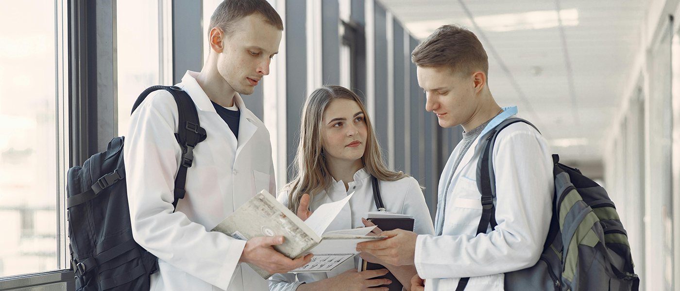 3 medical students standing talking in a corridor
