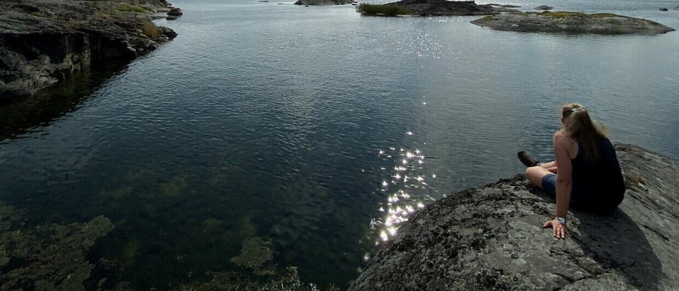 A woman sitting at the edge of a body of water