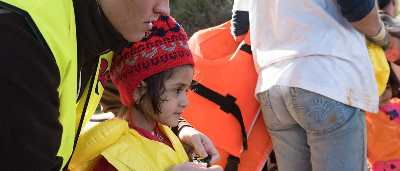 A child in a life jacket being comforted by a woman