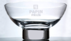 A close up image of a trophy bowl, which is clear, with a silver base, and the words HETC Papin Prize etched on the glass