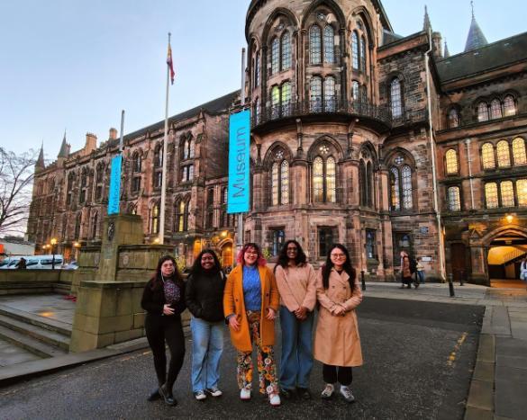 Rainbow Hours group standing outside, in front of the main University building