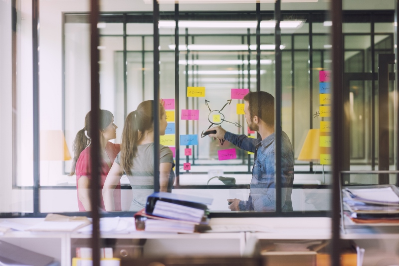 People working with post-it notes on a glass screen