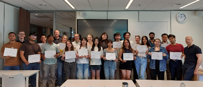 Students from ASBS and Radboud University standing together, holding their programme completion certificates, with a member of staff standing on either side of the group