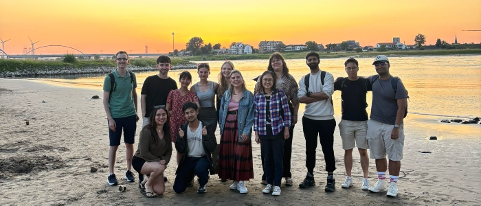 A group of ASBS students posing in front of the sunset on a beach in Nijmegen