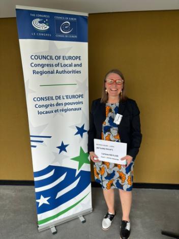 Professor standing in front of banner for council of europe